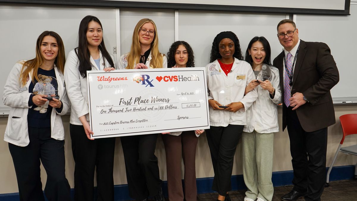 People hold a large check at the MCPHS Annual Capstone Business Plan Competition