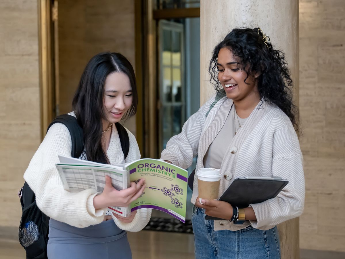 Two students looking at an Organic Chemistry book. 