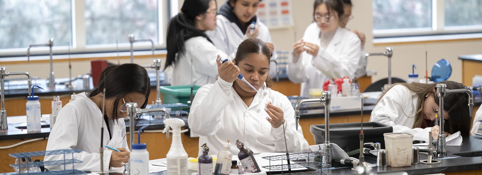 Student's working in big lab classroom, interacting with one another and the professors.