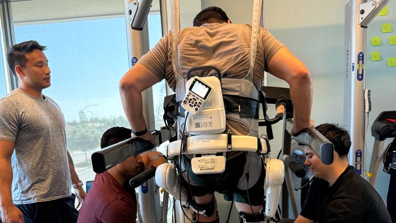 A physical therapist, Dr. Michael Vu, looks on as a patient wears the HAL exoskeleton on a treadmill.