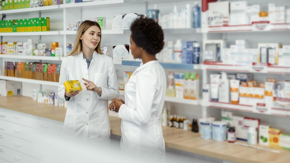 Two female pharmacists talking in a pharmacy.