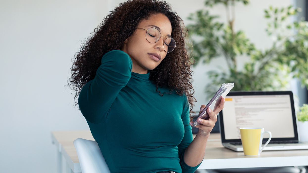 Woman holds neck while looking at phone.