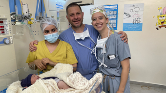 Three doctors and a baby in a hospital.