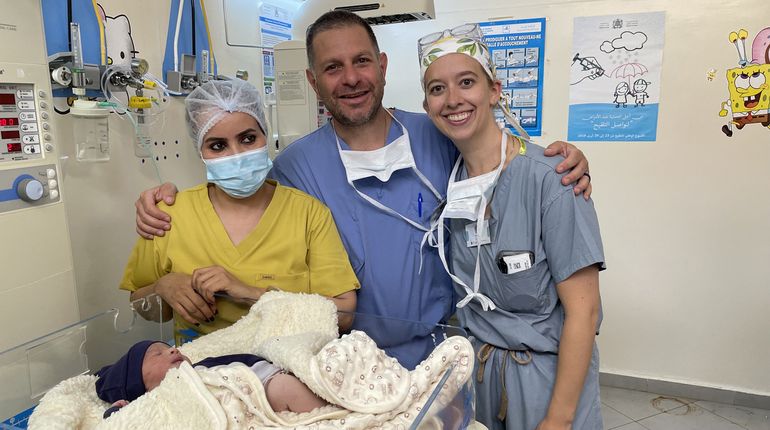 Three doctors and a baby in a hospital.