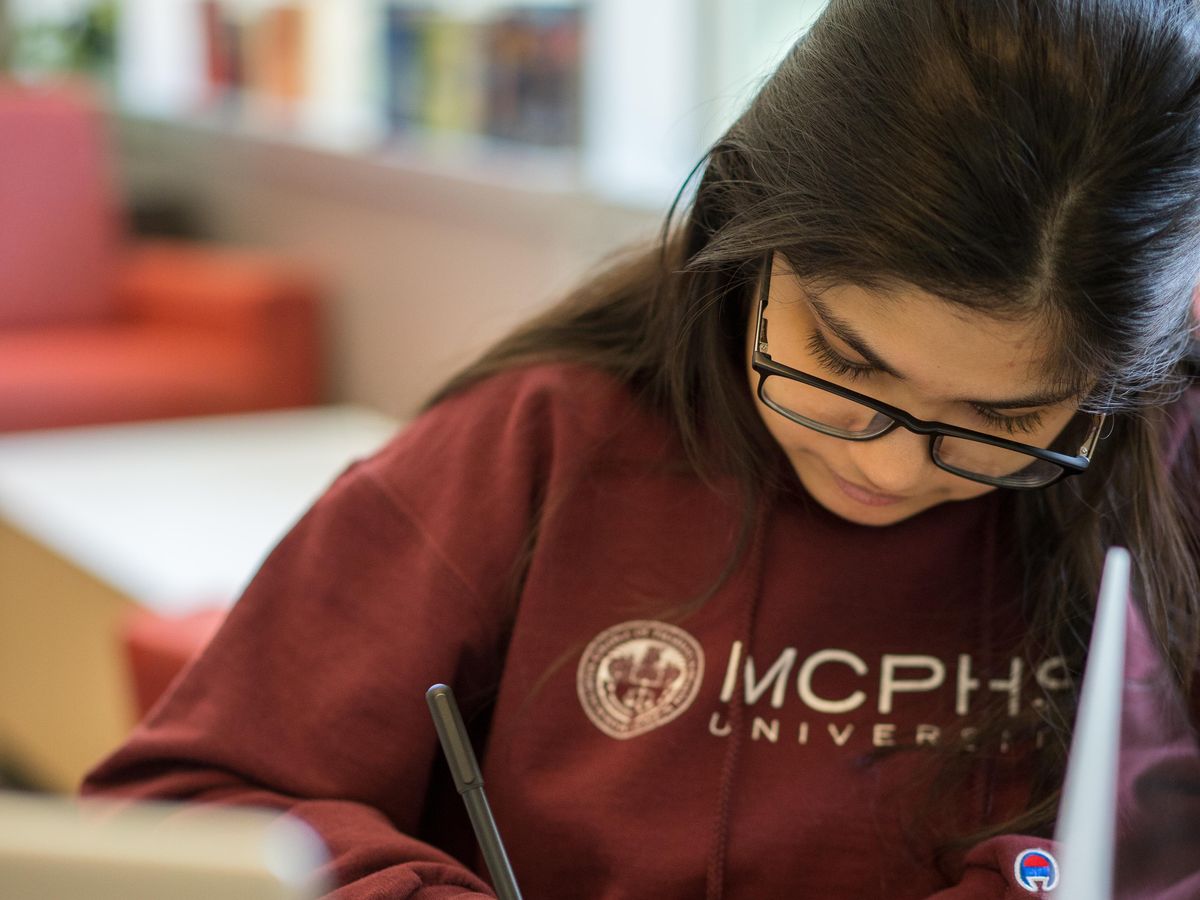 Female student writing with a pen. 