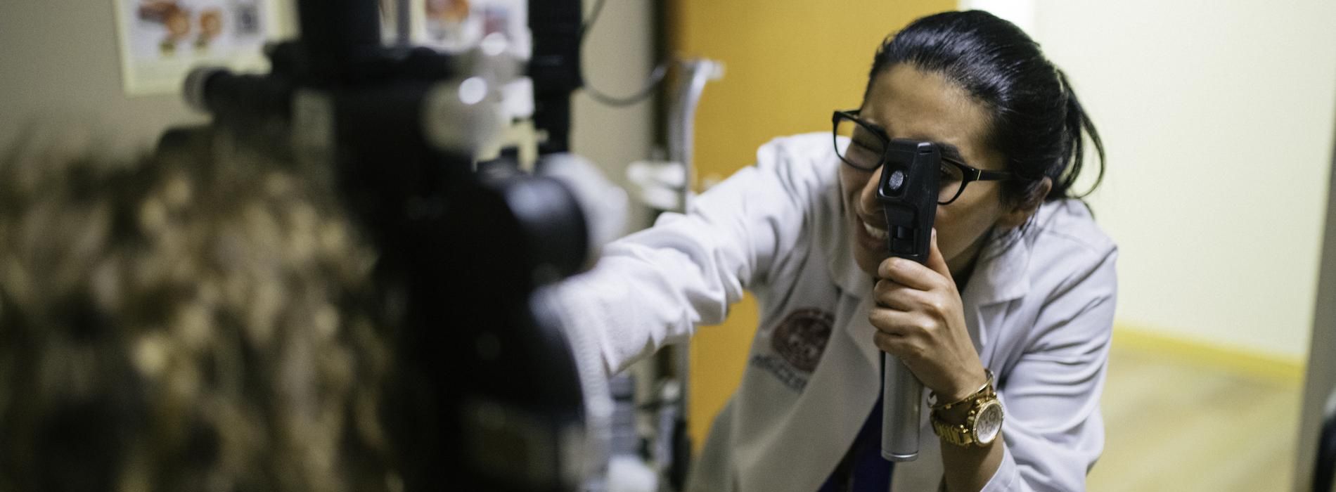 Female optometry student looking through a slit lamp.