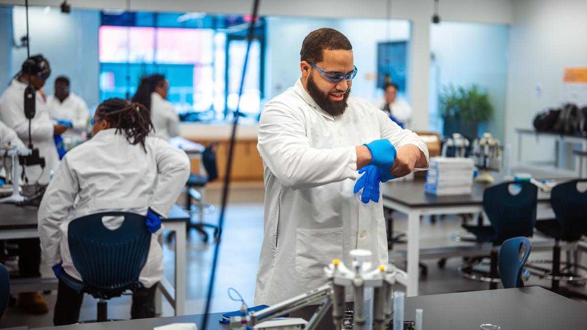 Male student in lab adjusts gloves.