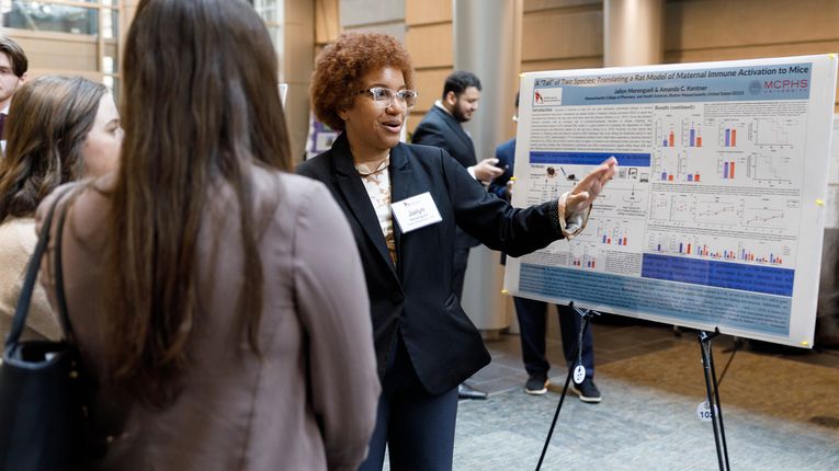 Woman stands in front of poster.