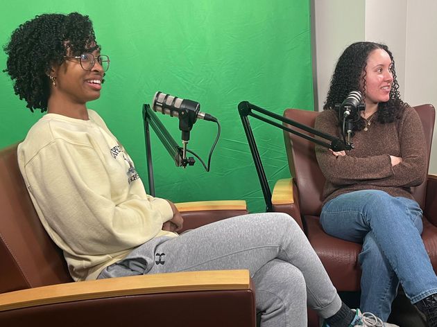Emily Obuseh and Kyleigh Hill sit in front of microphones.