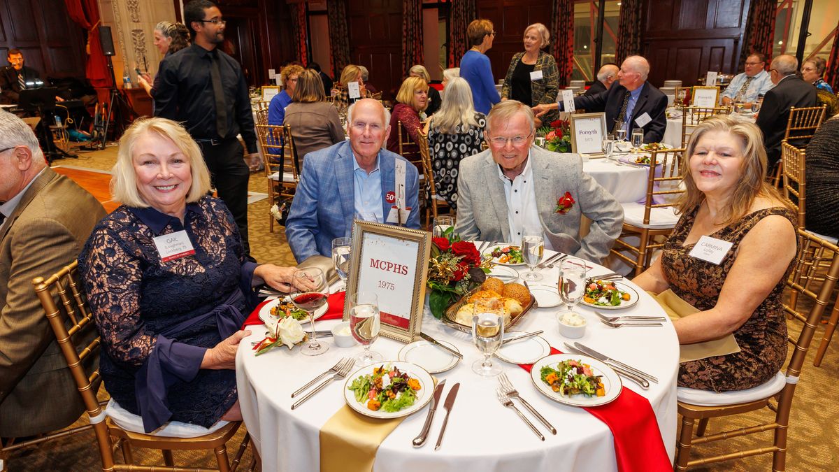 People sitting at a table at the MCPHS Golden Graduates Reunion.