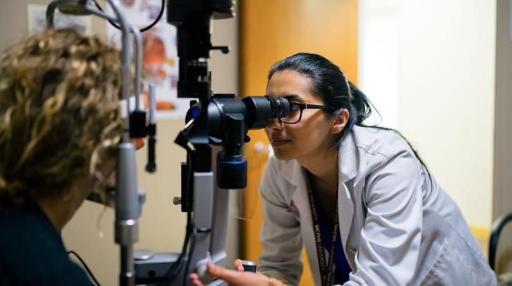 Female optometry student looking through a Phoroptor.