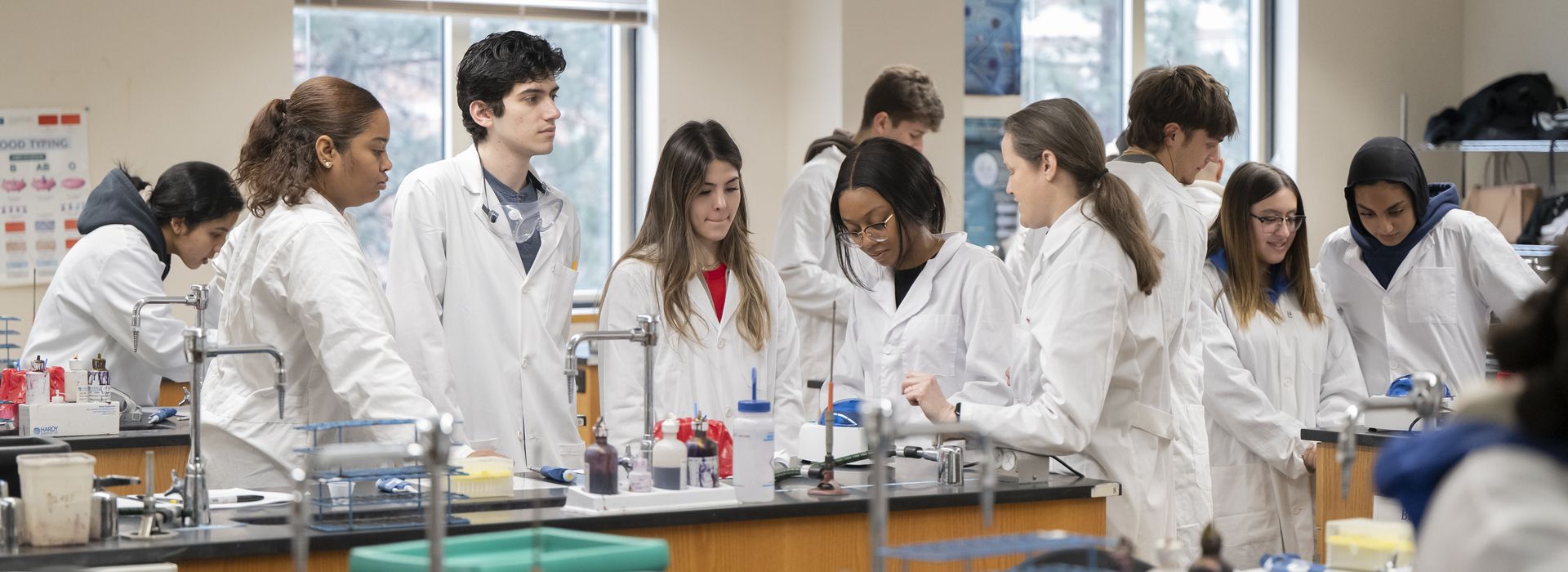 Student's working in big lab classroom, interacting with one another and the professors.