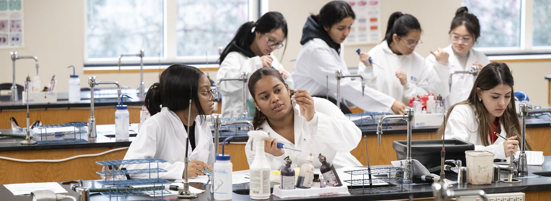 Student's working in big lab classroom, interacting with one another and the professors.