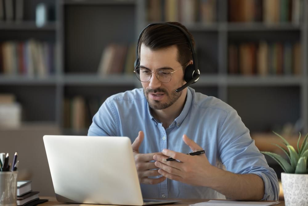 Male wearing a headset talking to a laptop. 